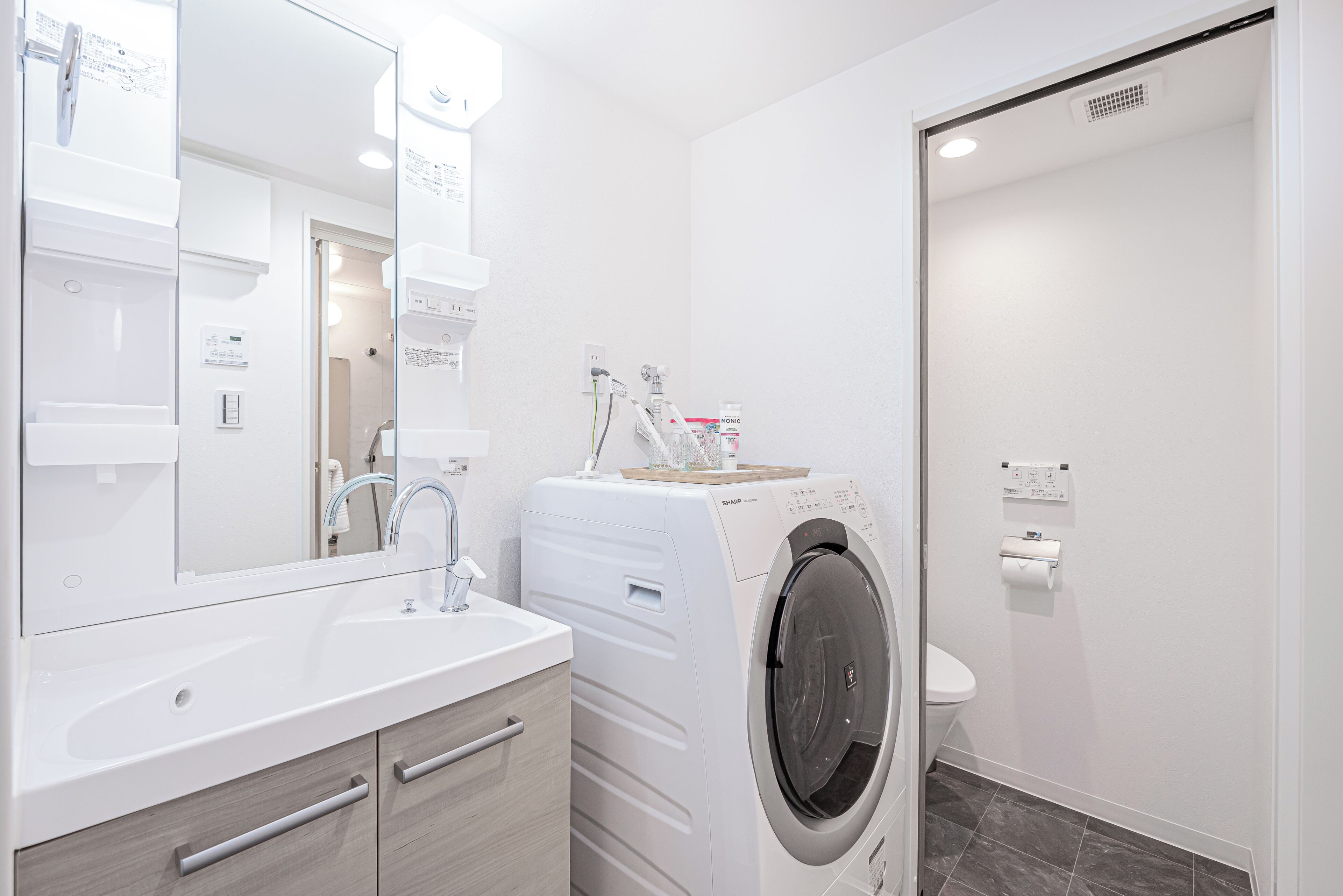 A modern bathroom with a built-in washing machine, a sink, and a toilet.