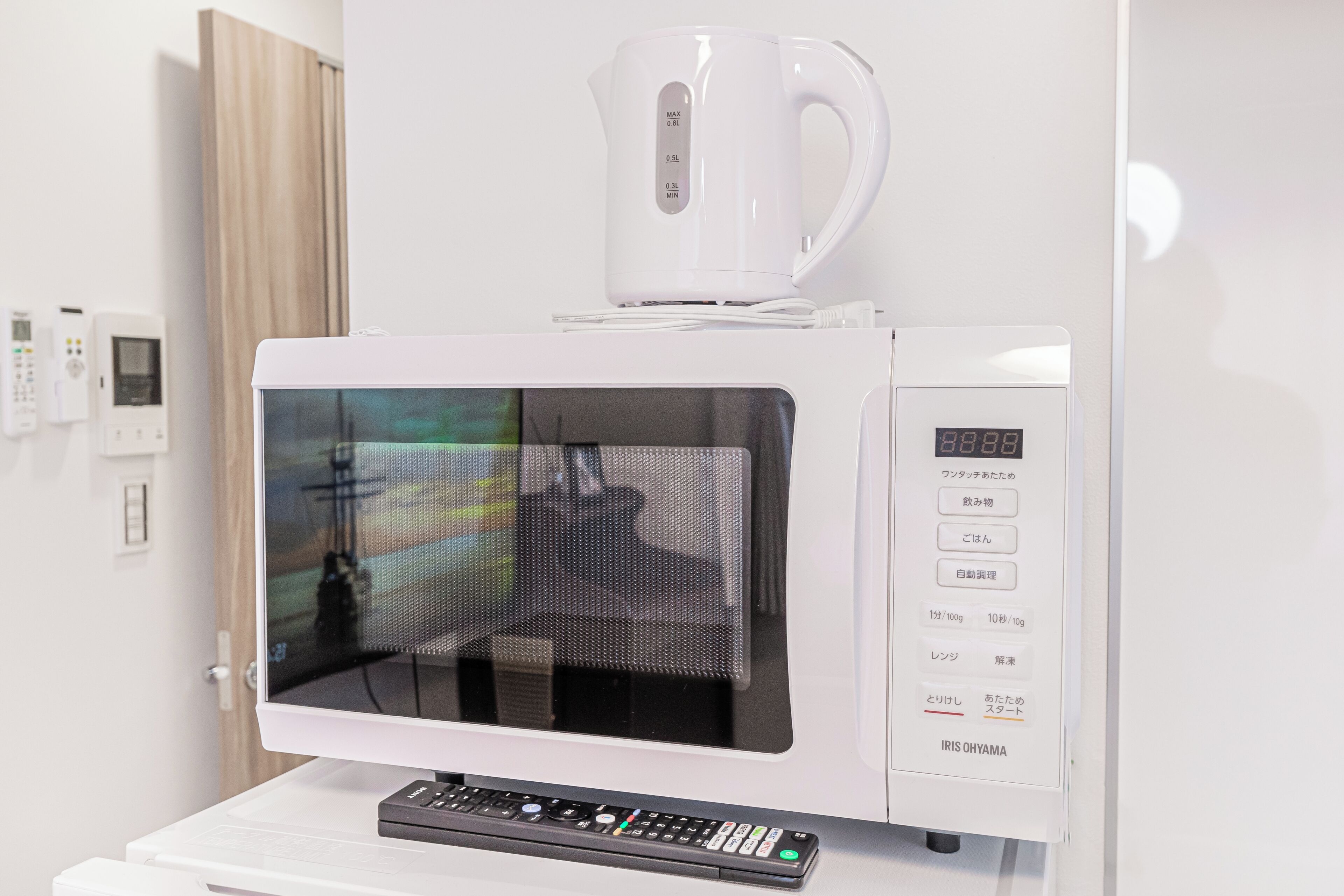A modern microwave with a digital display and a coffee maker on top.