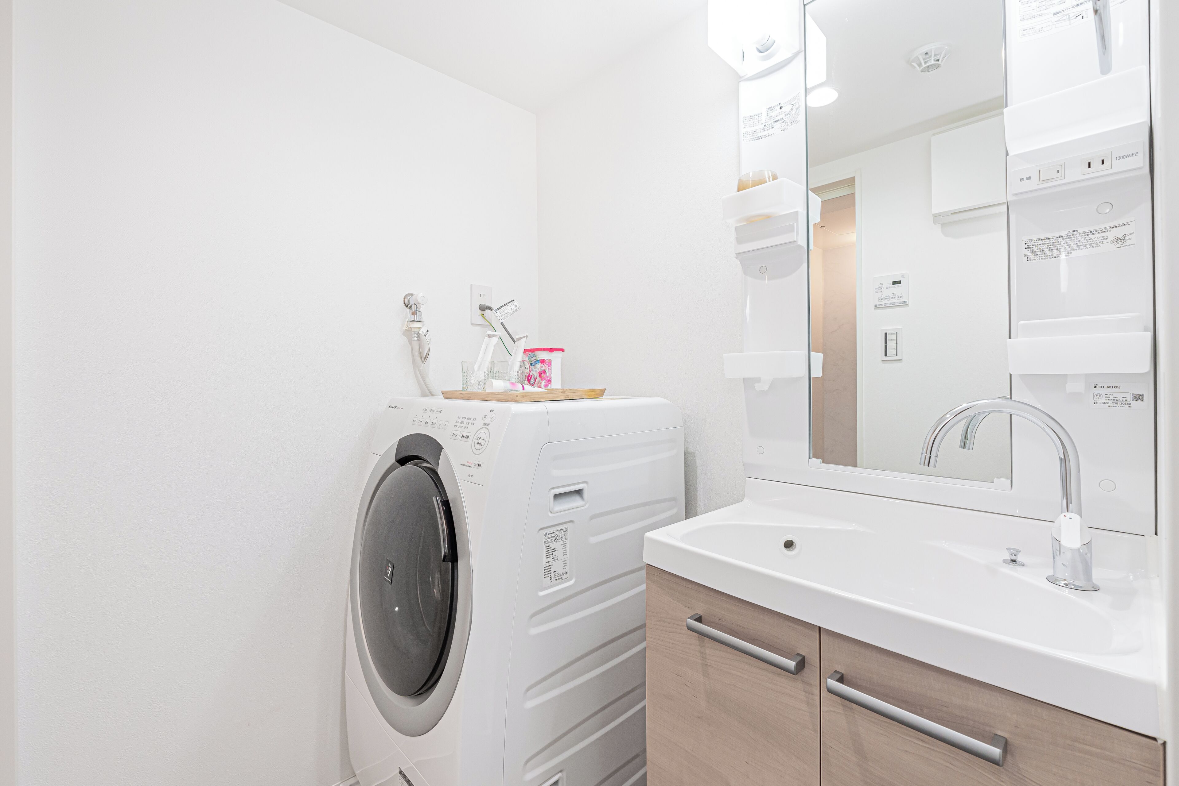 Een moderne badkamer met een wasmachine, een wastafel en een spiegel.