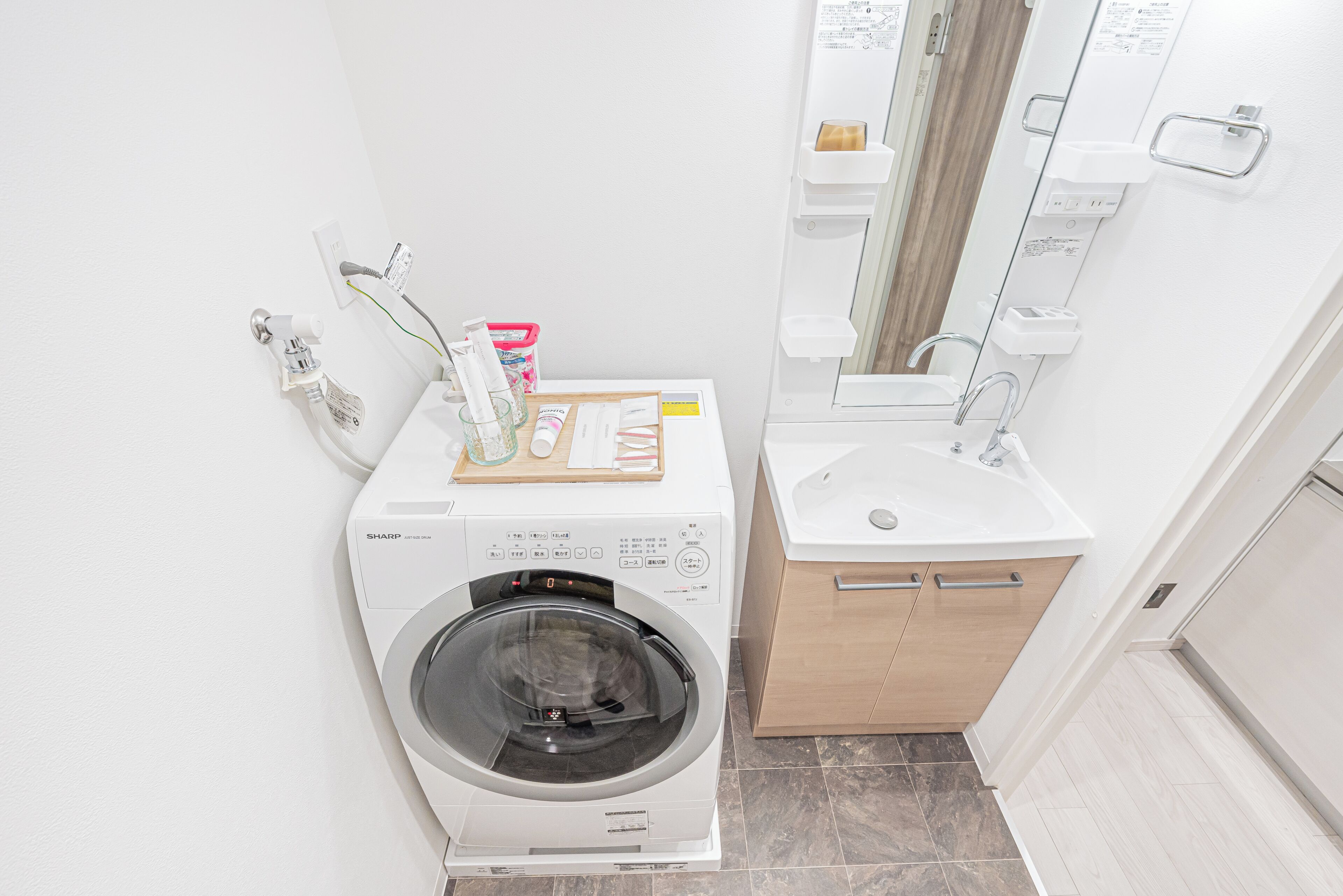 A compact laundry area with a washing machine, a small sink, and a mirror.
