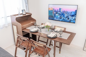 A dining area with a wooden table, chairs, and a cityscape painting on the wall.