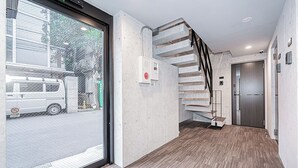 Un interior moderno con suelo de madera, una escalera y una puerta que da a una habitación.