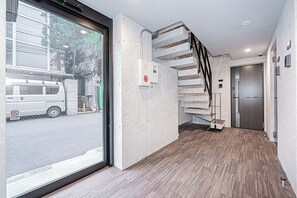 A modern interior with a wooden floor, a staircase, and a door leading to a room. - Shinjuku16 (Shinjuku-ku)