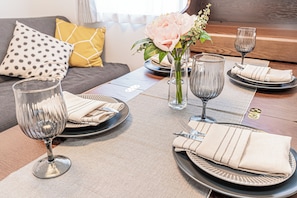 A dining table set with plates, cutlery, and glasses, with a vase of flowers in the center. - Shinjuku16 (Shinjuku-ku)
