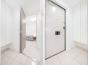A modern hotel room with a sliding door, a grey sofa, a bedside table, and a lamp. - Shinjuku16 (Shinjuku-ku)