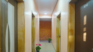 A hallway with doors numbered 107 and 106, leading to rooms. There are potted plants with pink flowers on the floor. - Hotel Shreekrupa Residency (Mahabaleshwar)