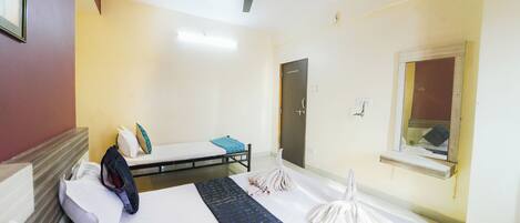 A hotel room with a bed, a desk, a ceiling fan, a window, and a door.