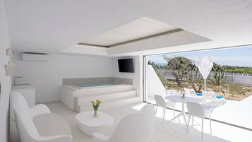 Interior moderno e claro, com televisão de tela plana, hidromassagem integrada e varanda com área de estar externa.