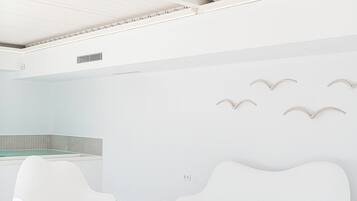 A modern, minimalist room with a white sofa, a round coffee table, and a small plant.