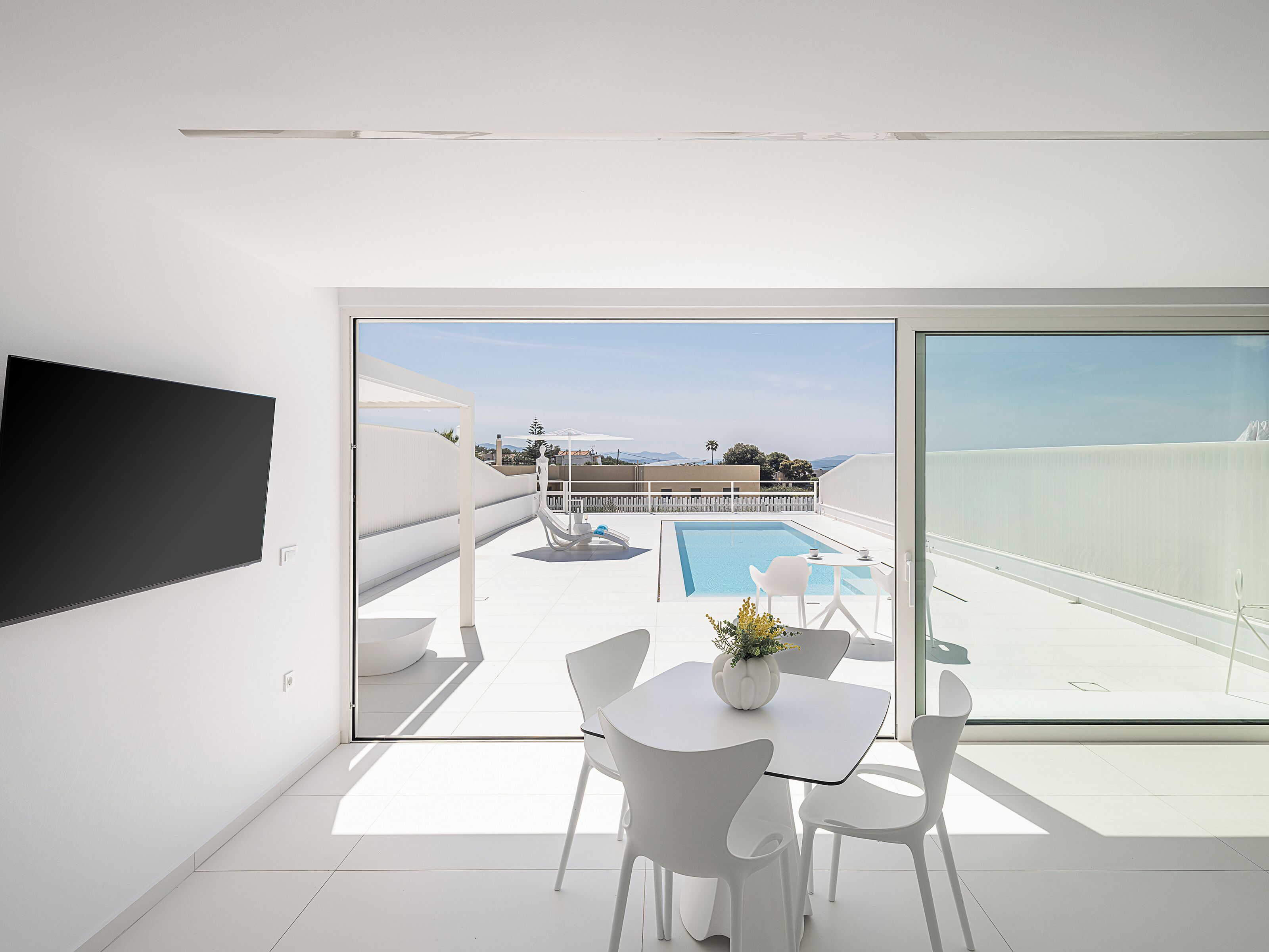 Un soggiorno moderno con una grande TV, una piscina e un balcone con vista.
