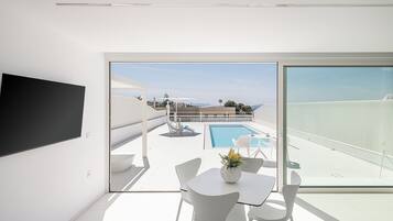 Un soggiorno moderno con una grande TV, una piscina e un balcone con vista.
