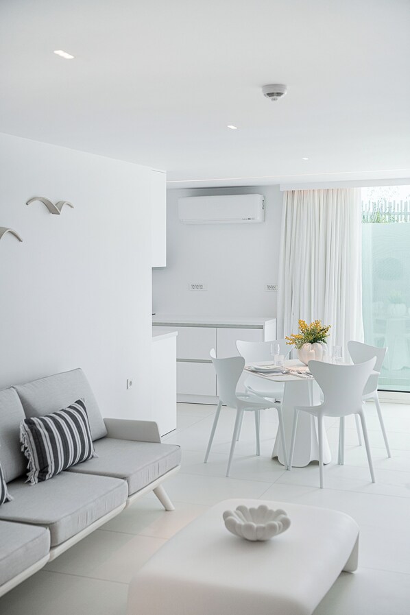 Un salon moderne et minimaliste, comprenant un canapé, une table à manger et des chaises.