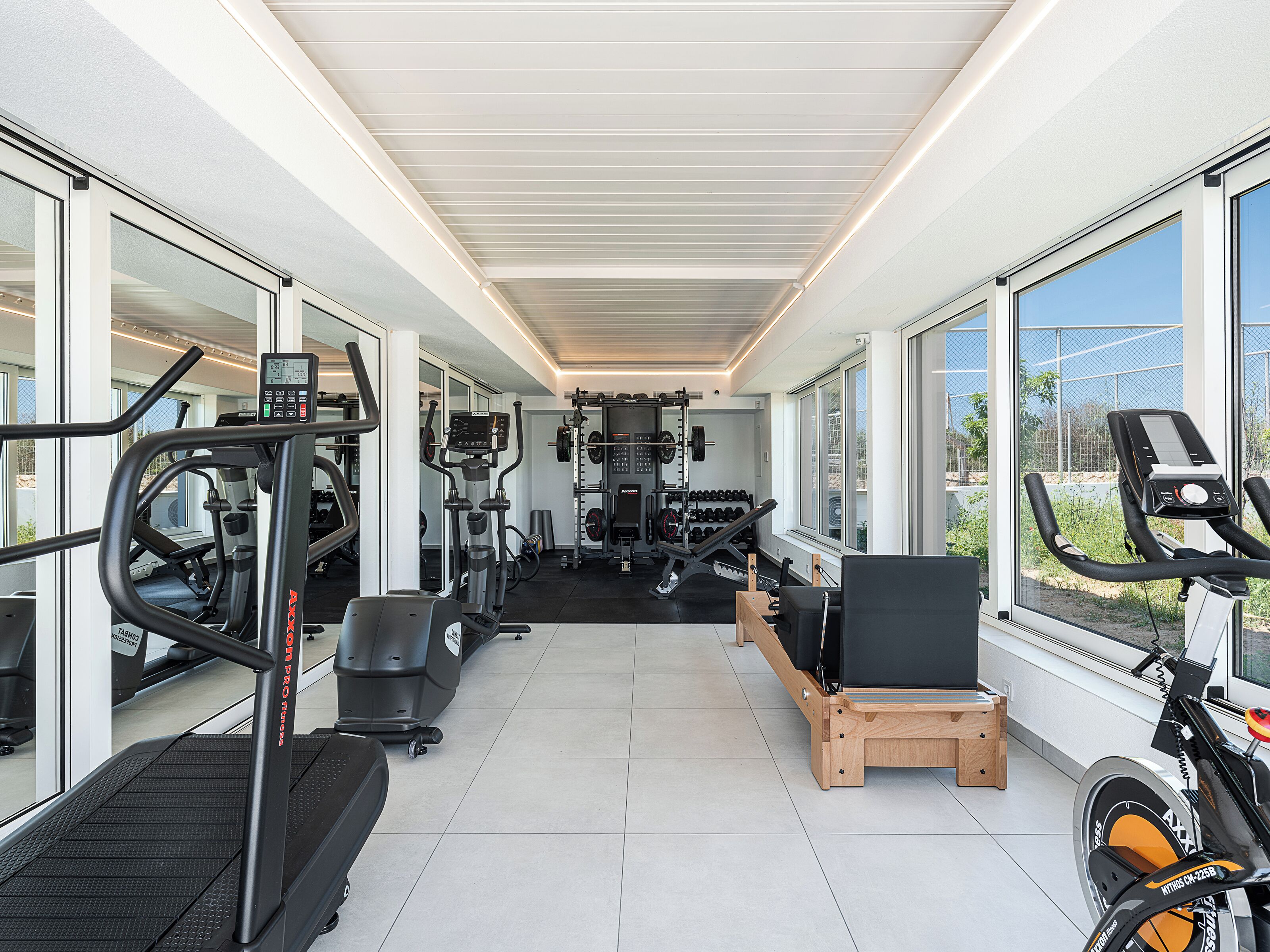A gym with cardio machines, free weights, and a weight rack.
