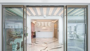 Een hotel receptie met een modern design, met een receptiebalie, een hanglamp en een glazen wand met uitzicht op het omliggende landschap.