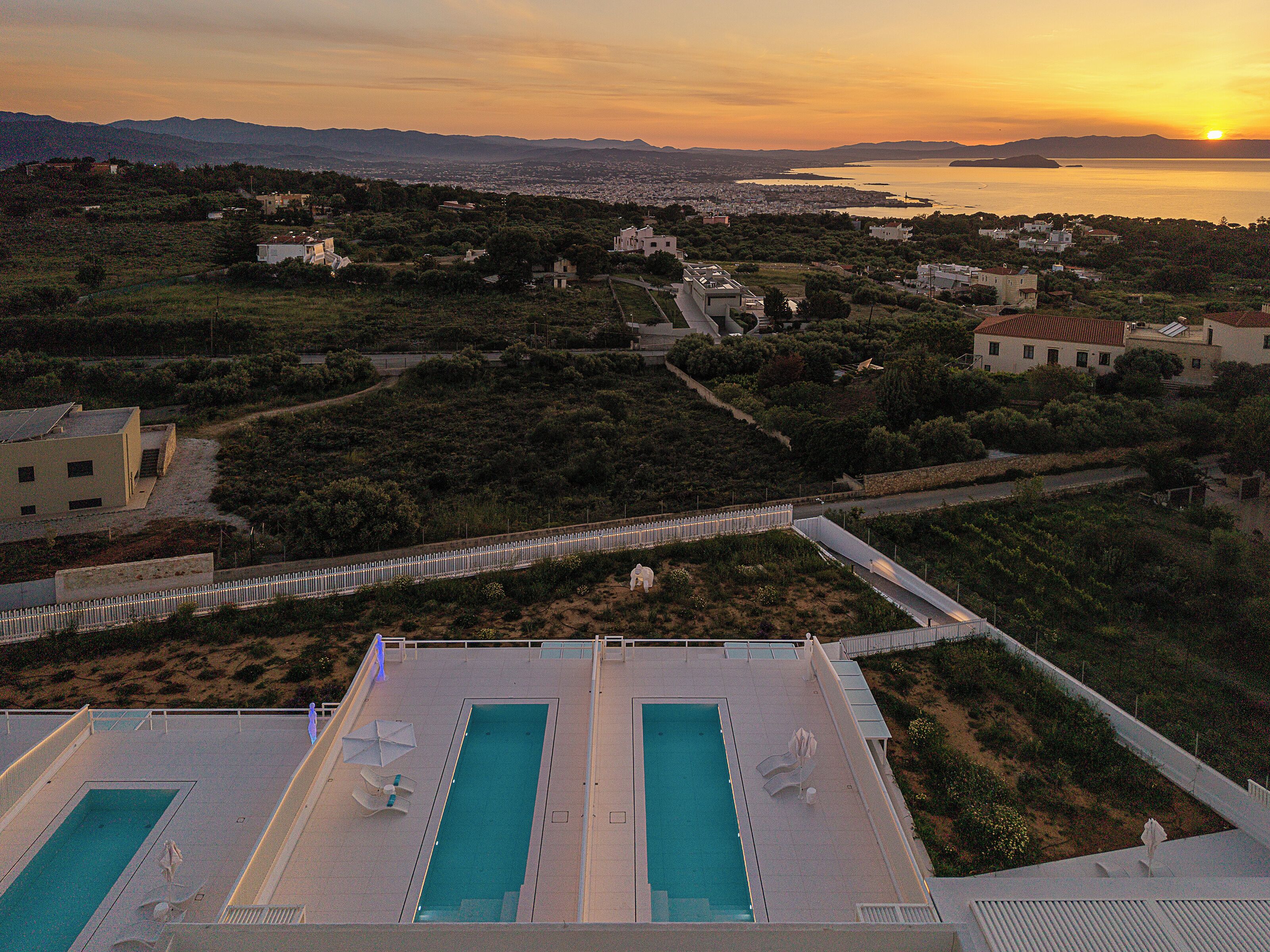 Ein Pool auf dem Dach mit Blick auf eine Stadtlandschaft und einen Sonnenuntergang.