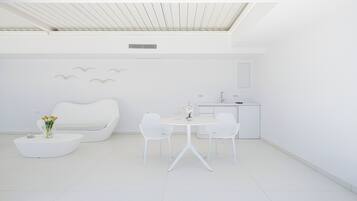 Una habitación moderna y minimalista con un sofá blanco, una mesa redonda y dos sillas.