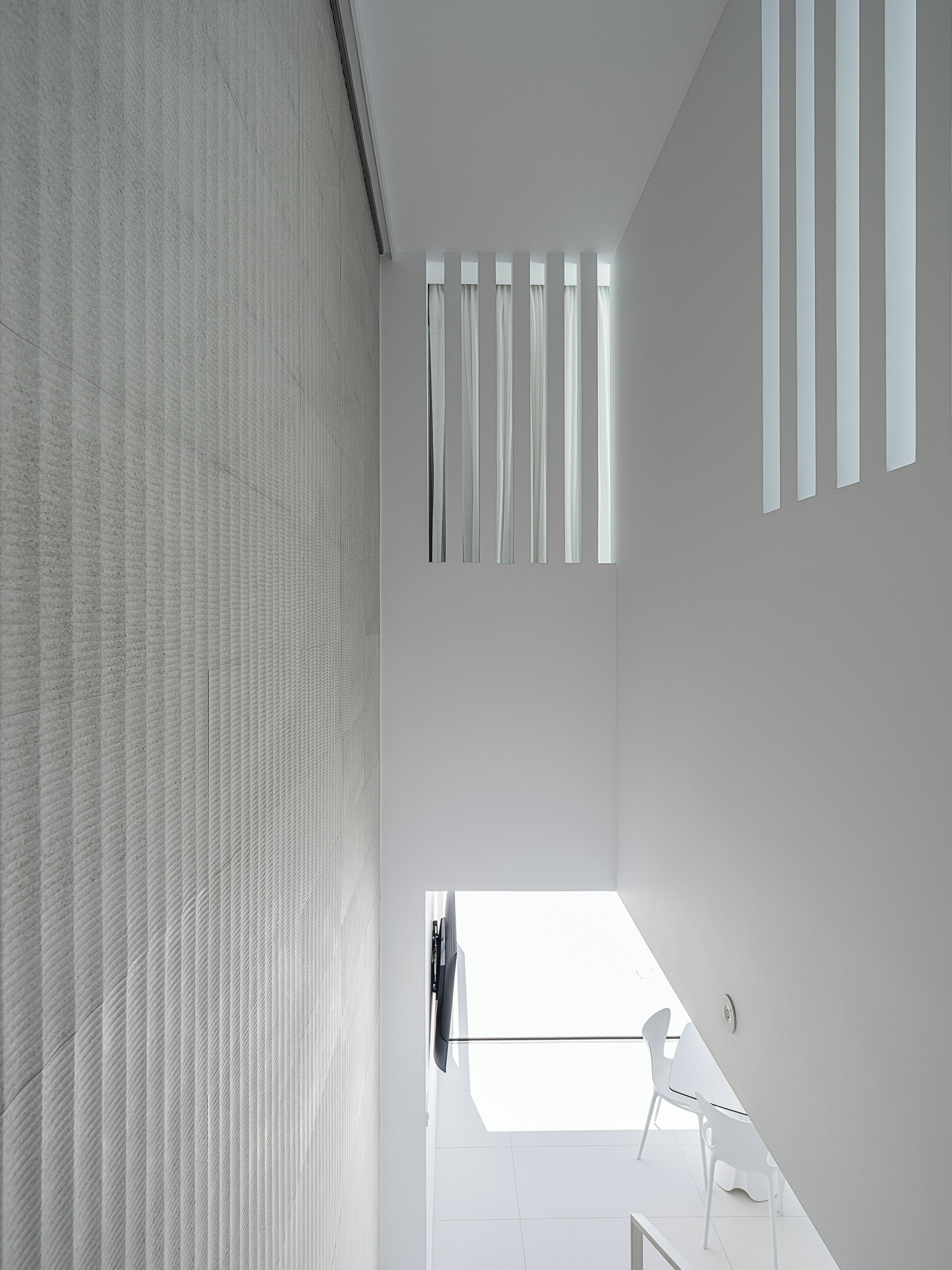 Een modern interieur met een hoge plafond, een schuine plafondconstructie en een uitzicht op de lucht door een raam.