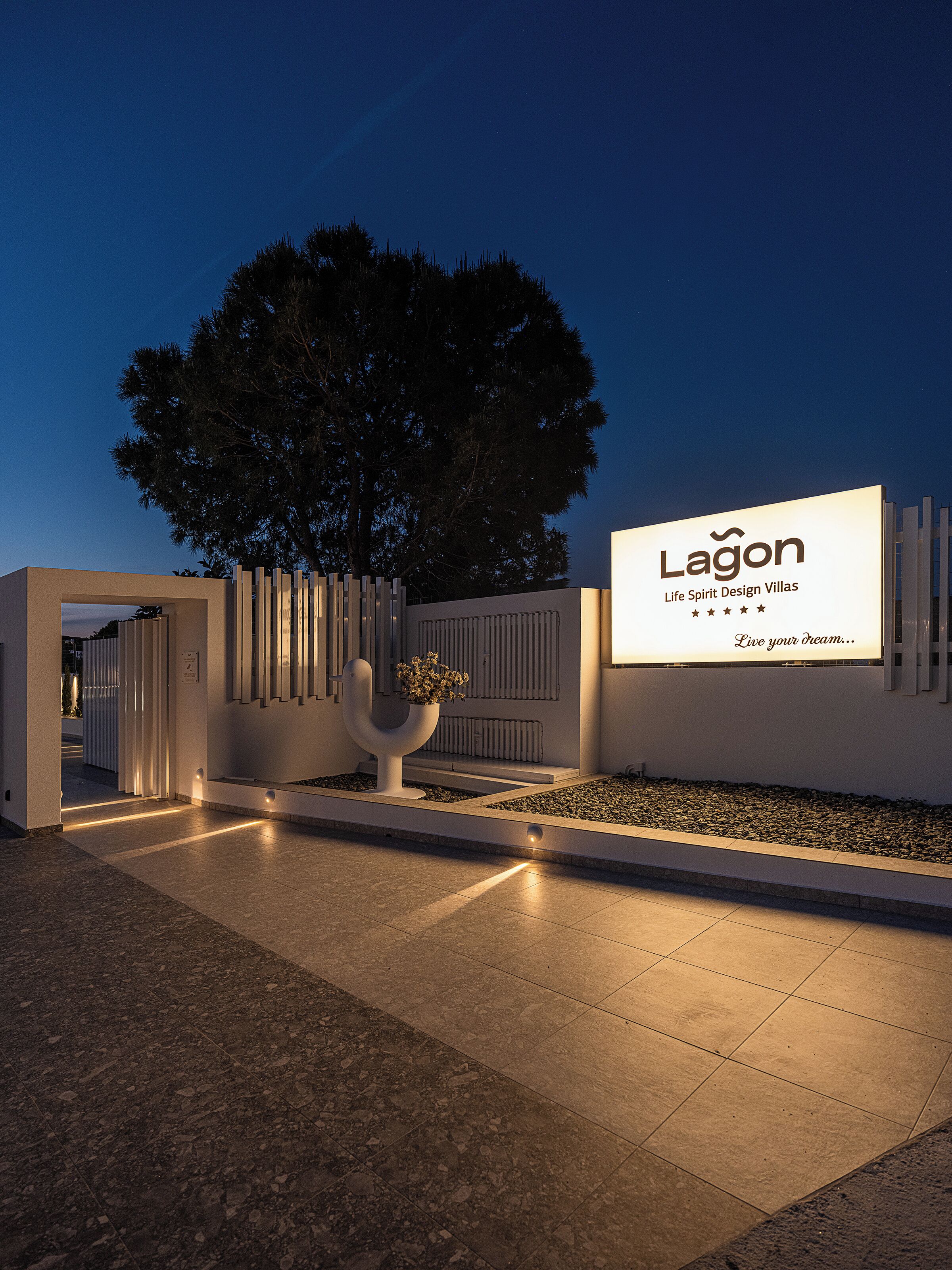 A modern entrance with a large illuminated sign for Lagón Life Spirit Design Villas.