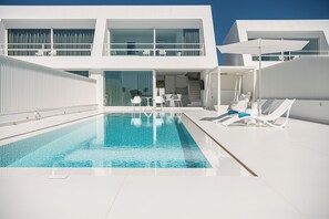 A modern pool area with a clear pool, white lounge chairs, and a two-story building with large windows and a balcony. - Lagon Life Spirit Design Villas - Adults Only (Chania)