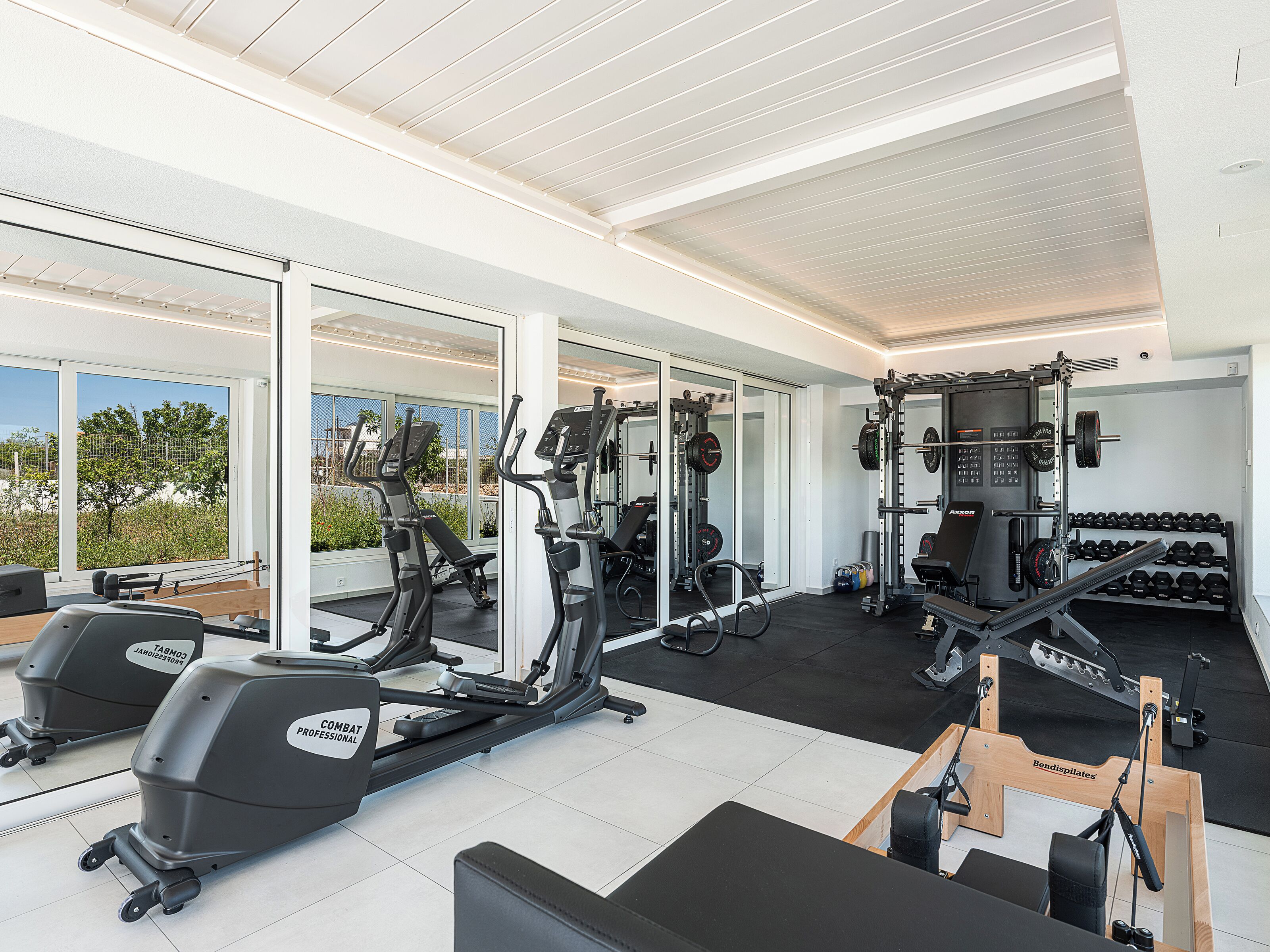 Een fitnessruimte met cardiotoestellen, krachthuishouding en dumbbells.