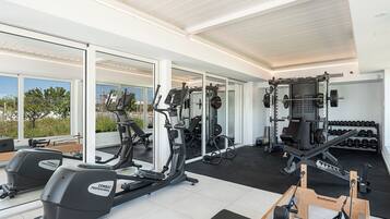 Een fitnessruimte met cardiotoestellen, krachthuishouding en dumbbells.
