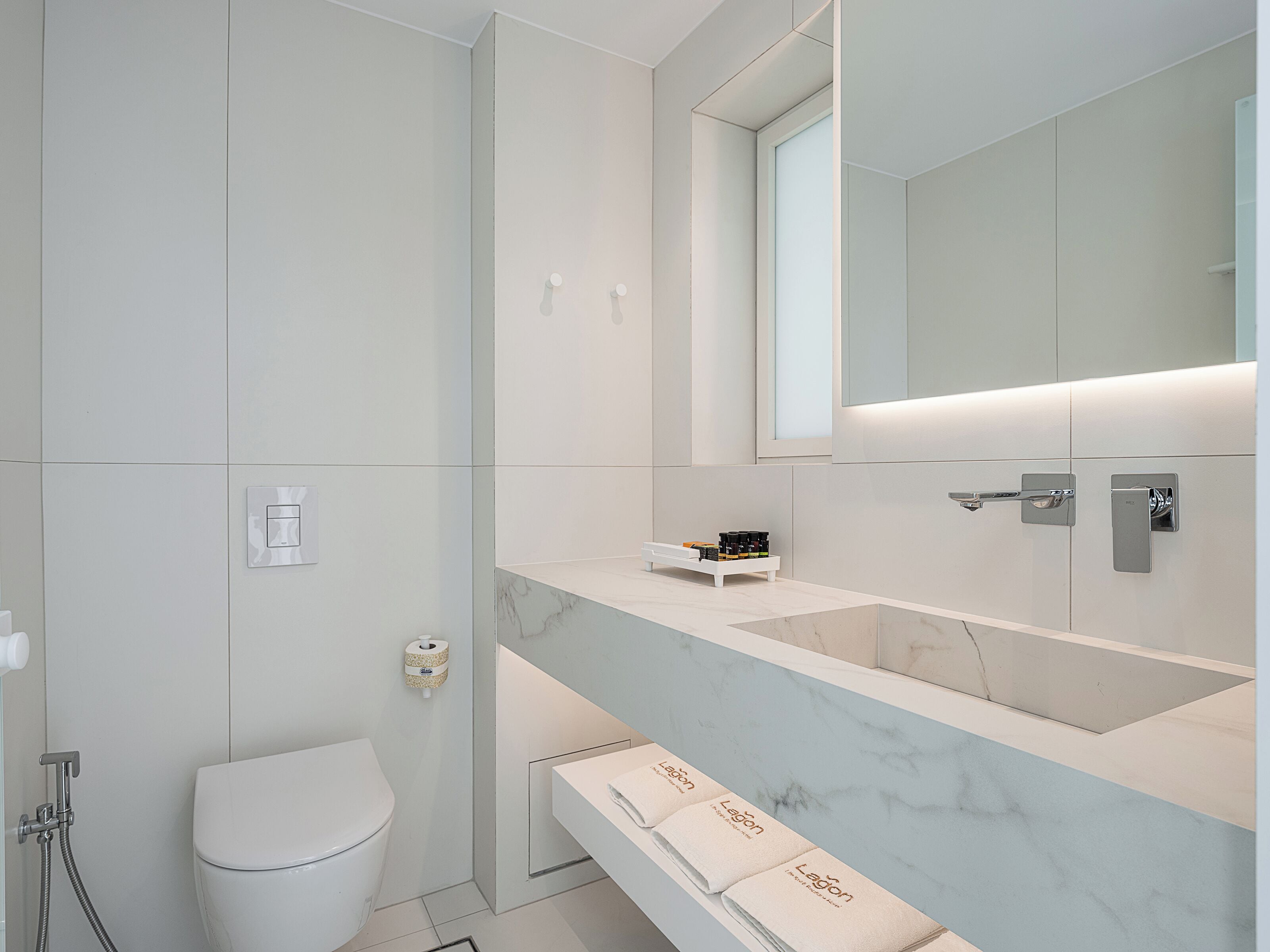 Un baño moderno con inodoro, ducha, lavamanos y espejo.