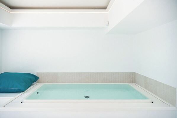 A small, modern bathroom with a bathtub, a teal pillow, and a light-colored wall. - Lagon Life Spirit Design Villas - Adults Only (Chania)
