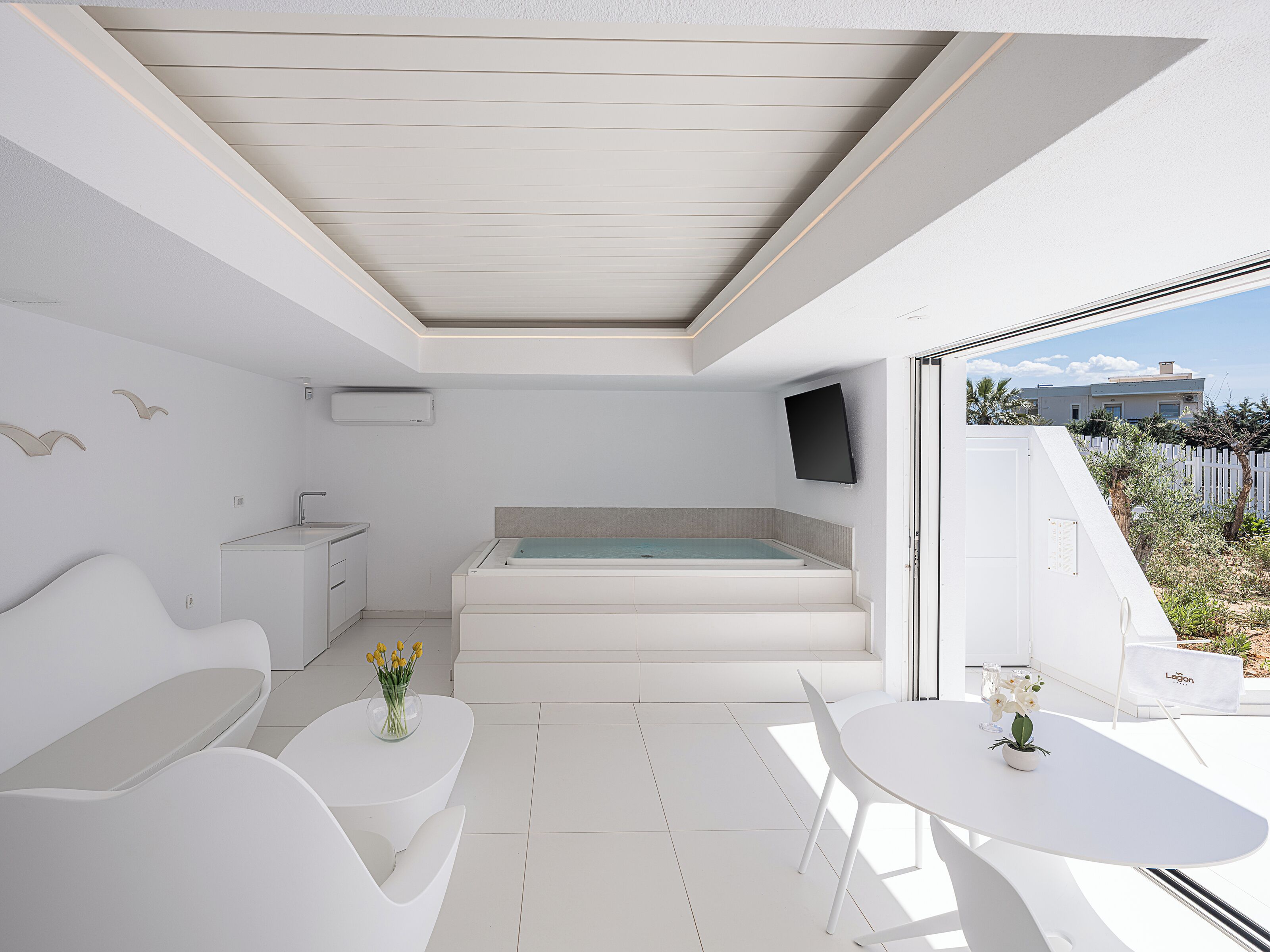 A modern bathroom with a bathtub, a sink, and a toilet. There is a small table with a vase of flowers.