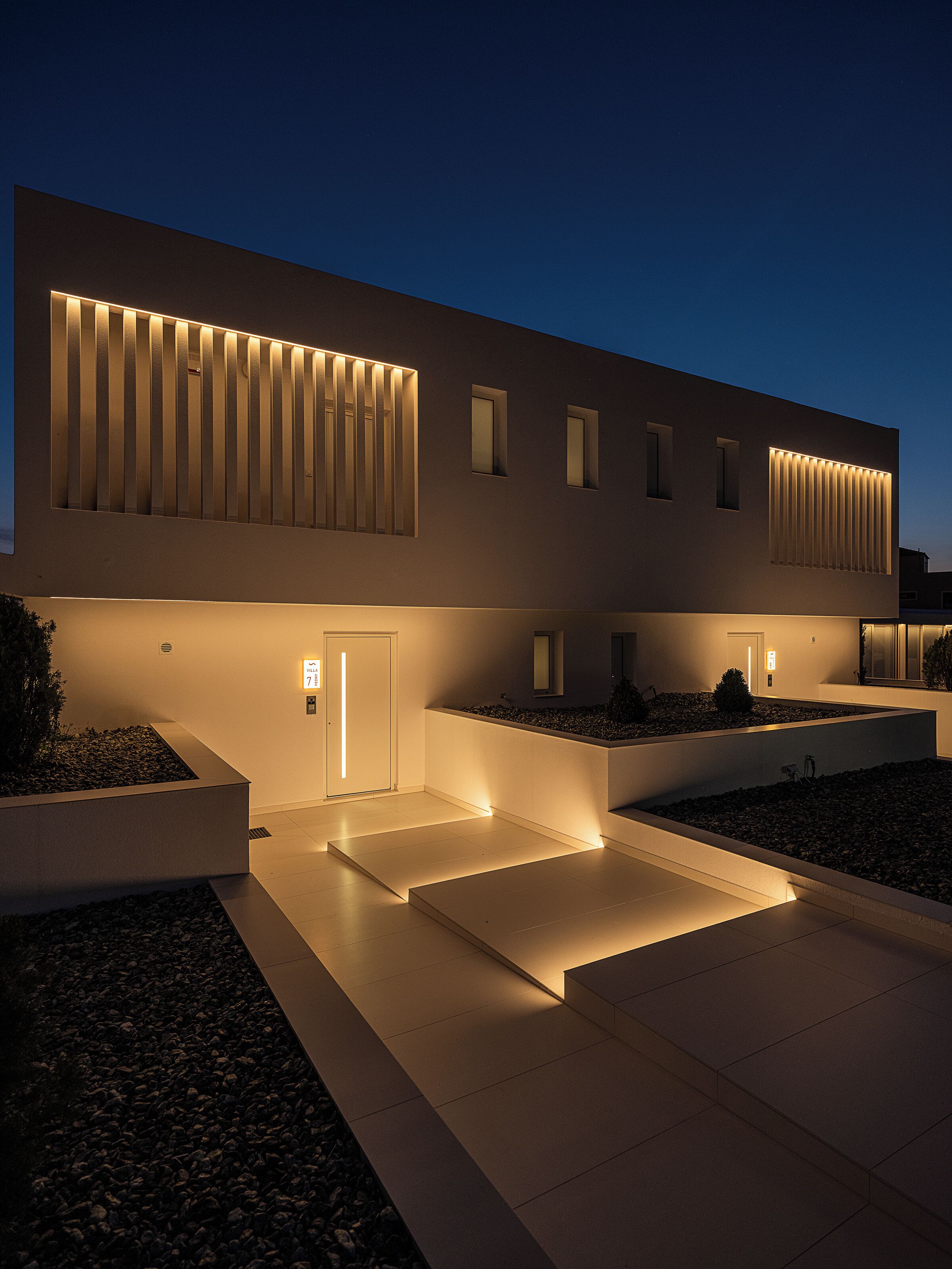 Een modern gebouw met een plat dak, grote ramen en een goed verlichte ingang.