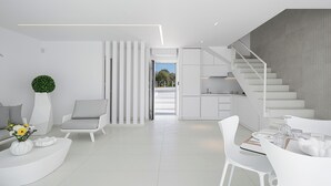 Een modern interieur met een trap, witte meubels en een uitzicht door een deuropening.