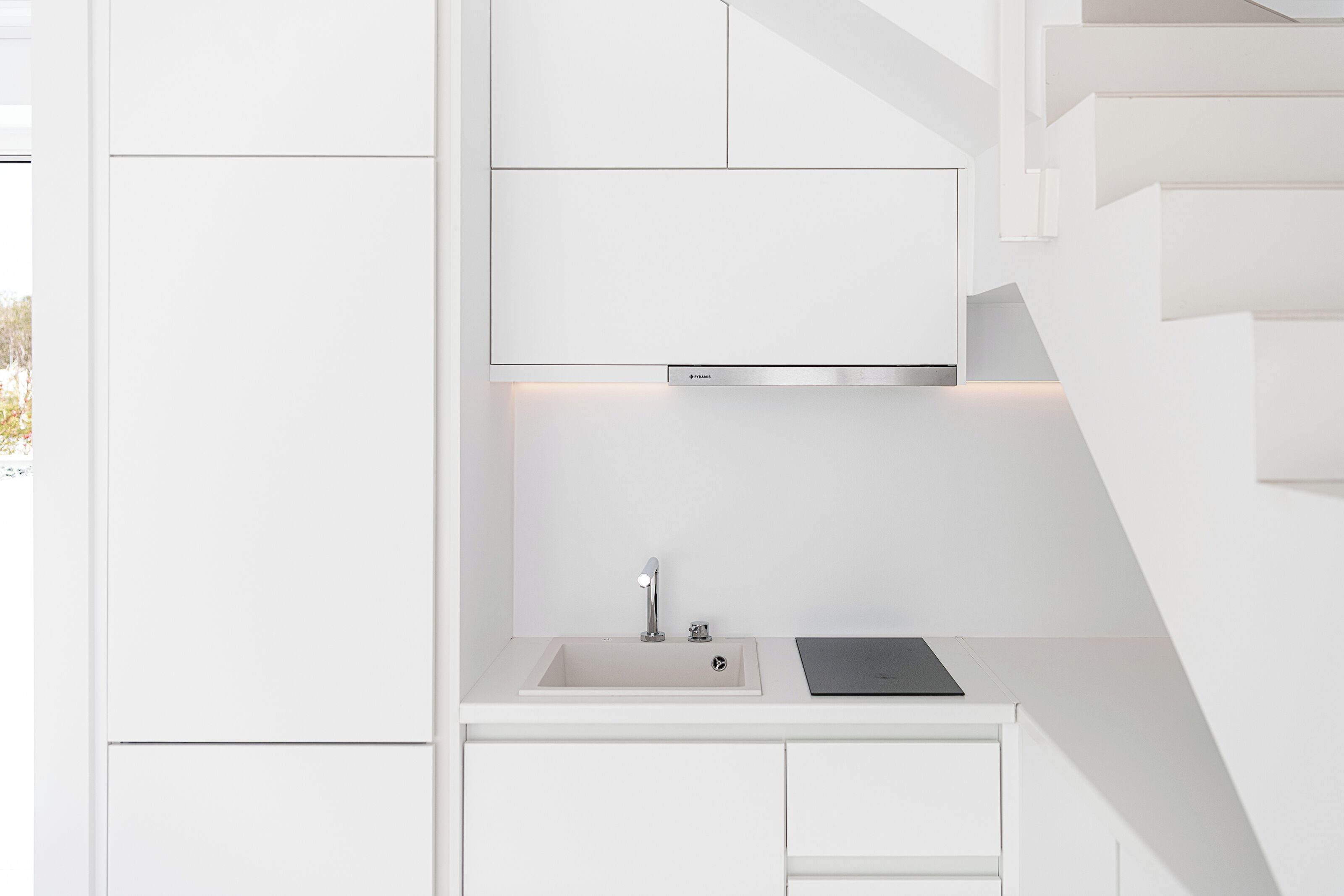 A modern kitchen with a built-in sink, stainless steel faucet, and a black tablet on the countertop.