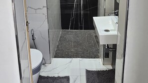 Et moderne badeværelse med en glasbrusekabine, en hvid vask og toilet.