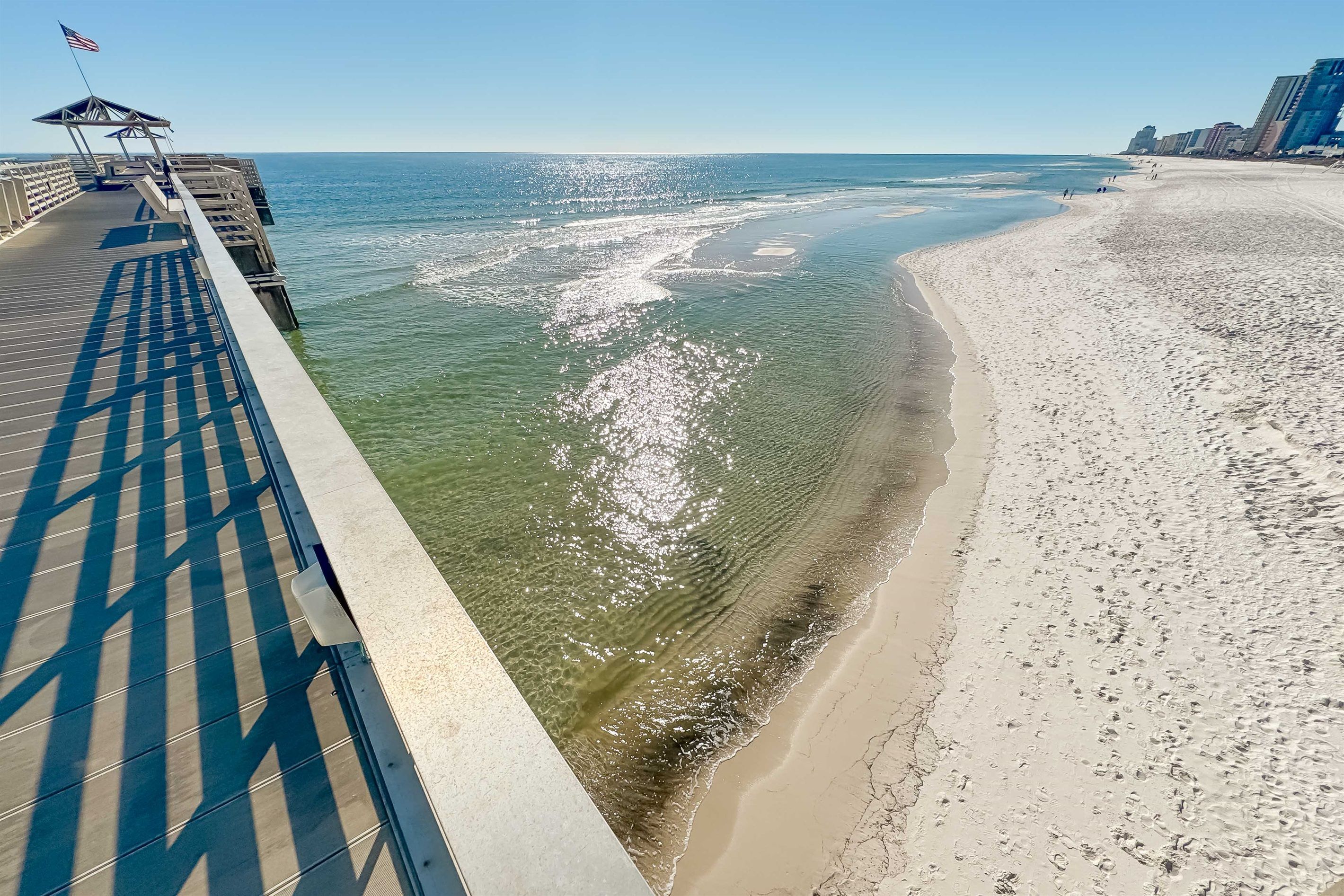 A pier extending into the ocean with a clear view of the beach and ocean.