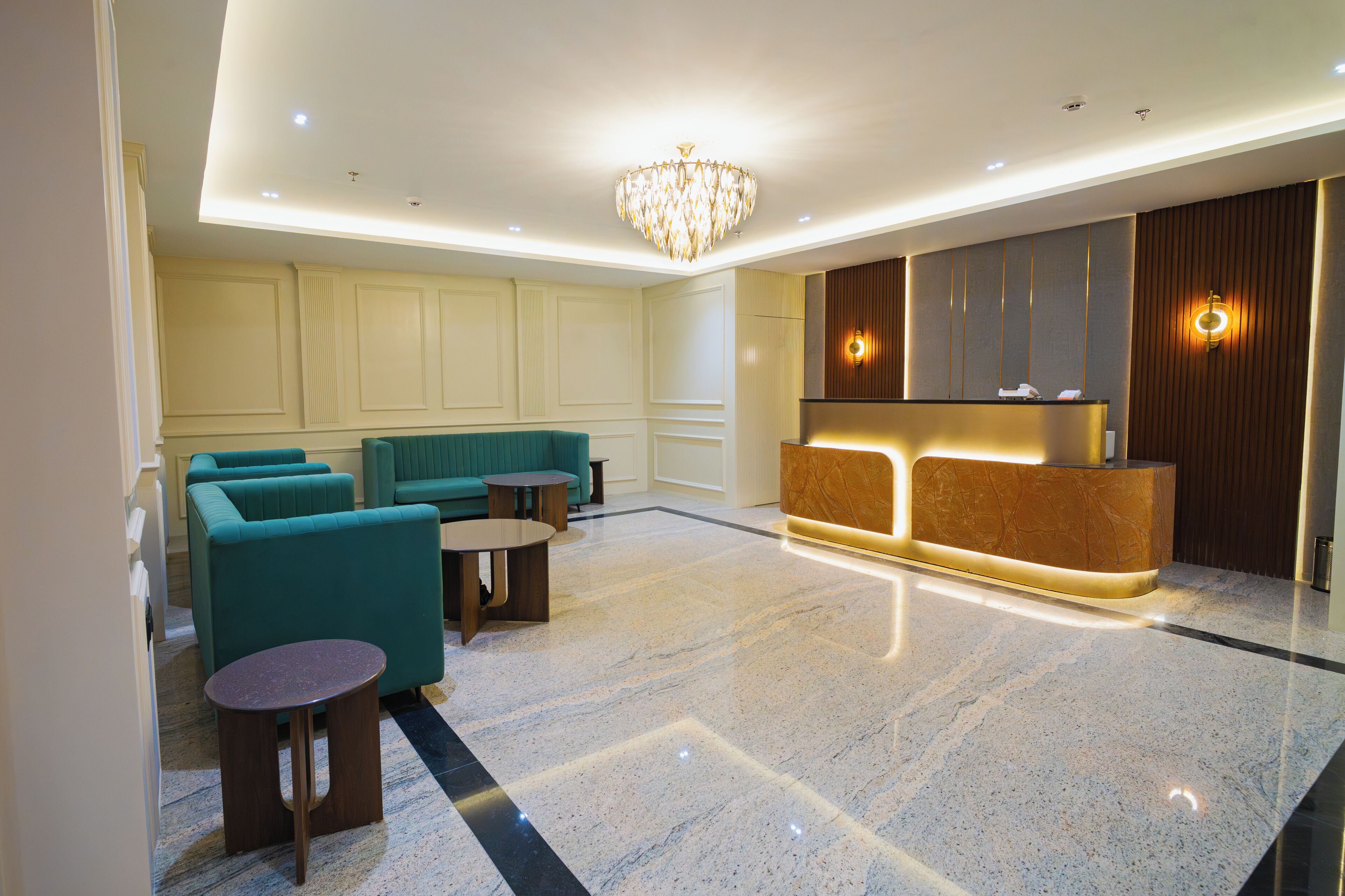 A lobby with teal sofas, a reception desk, and a chandelier.