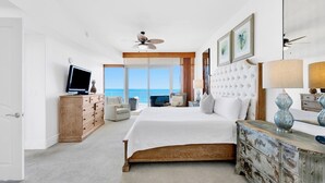 A spacious bedroom with a large bed, a television, a wooden dresser, and a view of the ocean. - Breathtaking beach views from every room! Spacious, luxurious, hot tub and grill on private balcony! (Orange Beach)
