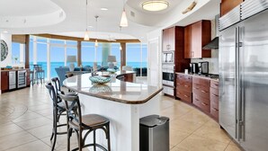 A modern kitchen with a central island, stainless steel appliances, and a view of the ocean. - Breathtaking beach views from every room! Spacious, luxurious, hot tub and grill on private balcony! (Orange Beach)