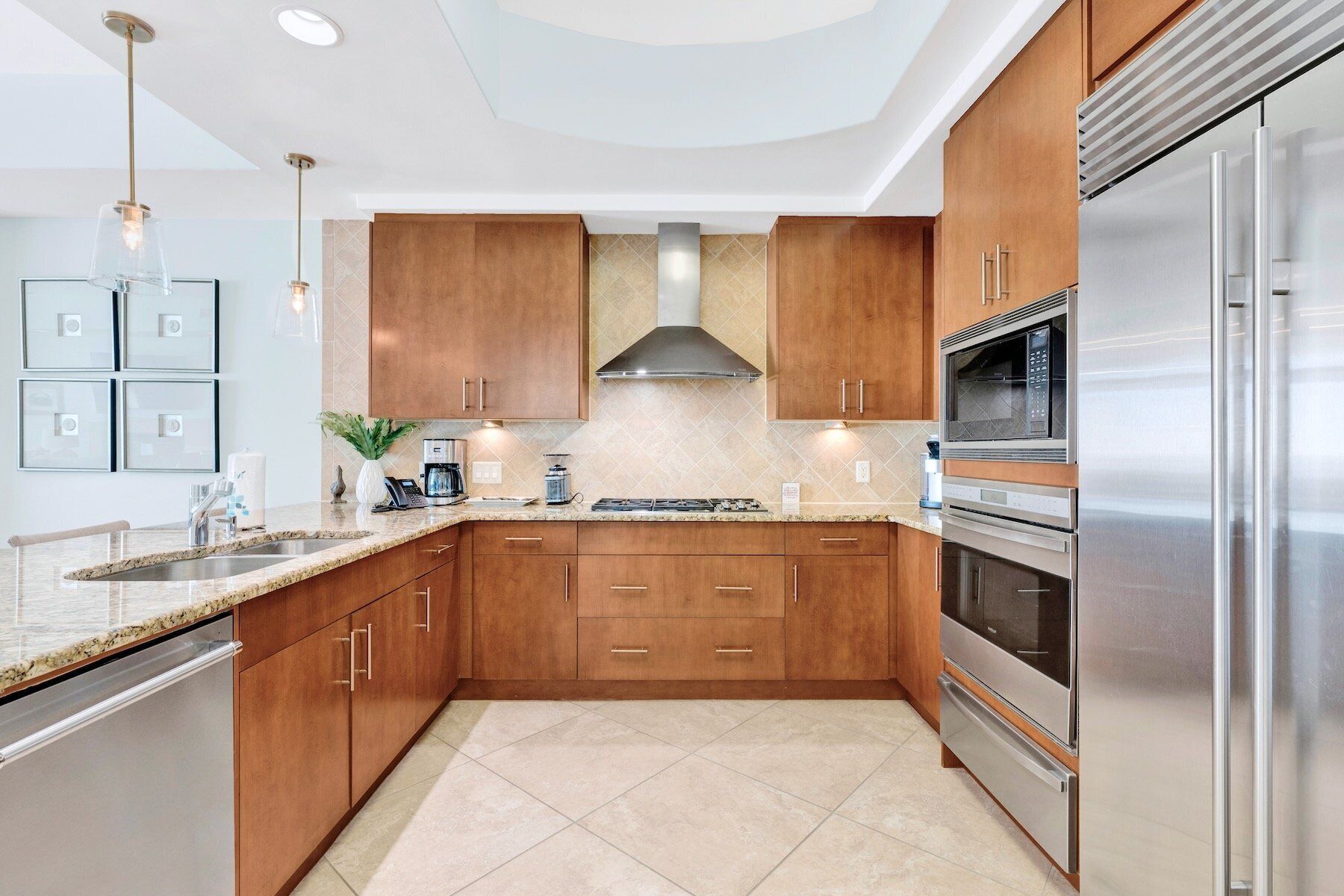 A modern kitchen with wooden cabinets, stainless steel appliances, and a granite countertop.