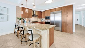 A modern kitchen with a central island, stainless steel appliances, and wooden cabinets.