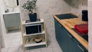 A modern kitchen with marble tiles, a wooden countertop, a built-in oven, and a microwave on a shelf. - T2 furnished 30 m² with private courtyard - Maison en pierre meulière - Ivry-sur-Seine (Ivry-sur-Seine)