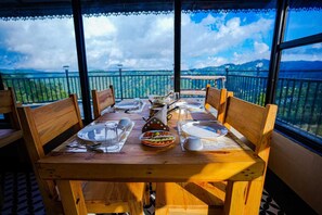 A dining table set for four with a view of mountains and a clear sky. - Aurora Ridge Residence (Dhari)