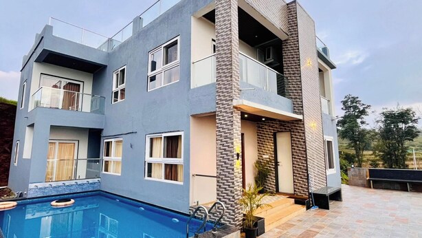 A modern two-story house with a swimming pool, balconies, and a stone facade. - Suketi Stays (Mahabaleshwar)