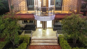 A two-story house with a balcony, a staircase leading to the entrance, and a garden area. - Suketi Stays (Mahabaleshwar)