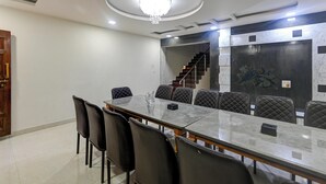 A conference room with a marble table, black chairs, a chandelier, a staircase, and a decorative wall. - Suketi Stays (Mahabaleshwar)
