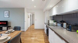 Una cocina moderna con encimera de madera, electrodomésticos integrados y un comedor con mesa preparada para dos personas.
