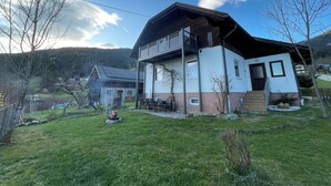 Uma casa de dois andares com varanda, chaminé e um gramado.