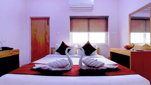 A hotel room with a bed, a desk, a mirror, and a window with curtains. - Hotel Chaitrangada (Bolpur)