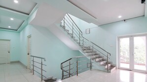 A staircase with metal railings, a door, and a large window. - Hotel Chaitrangada (Bolpur)