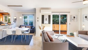 A modern living space with a dining area, a sofa, and a balcony with a view. - Resort Mediterra | Sea View Apartment near Golf with Pools & Fitness (Benalmádena)