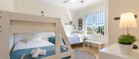 Une chambre avec un lit superposé, un bureau, une chaise, une lampe et une fenêtre donnant sur un beau paysage.