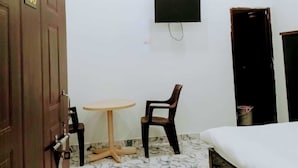 A room with a bed, a desk, a chair, an air conditioner, and a ceiling fan. - S K Homestay (Varanasi)